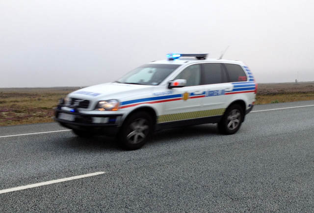 Hékk framan á vélarhlíf bifreiðar á ferð